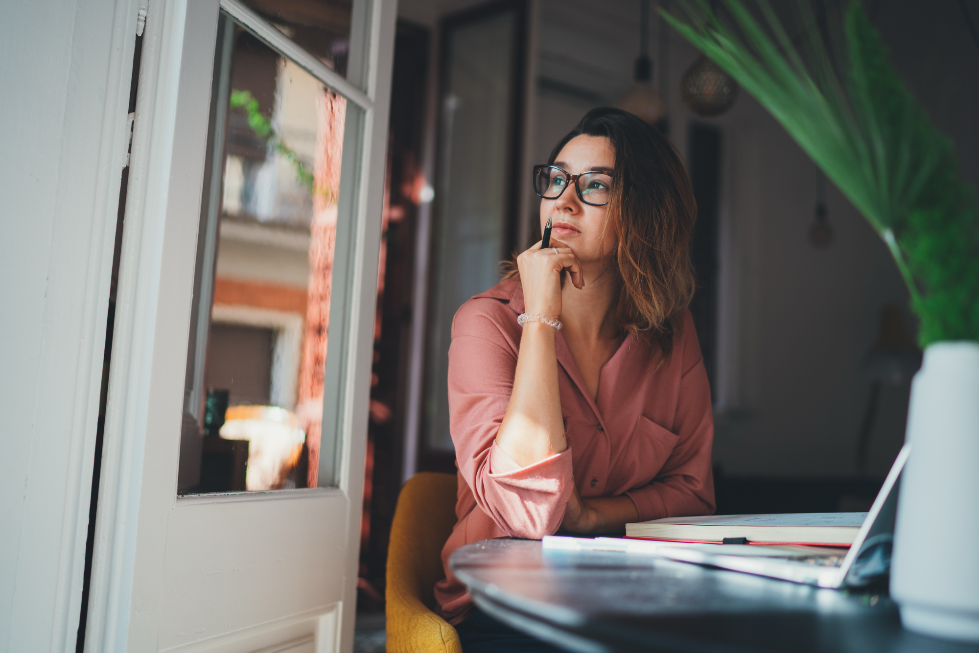 A small business owner thinking at her desk with a laptop